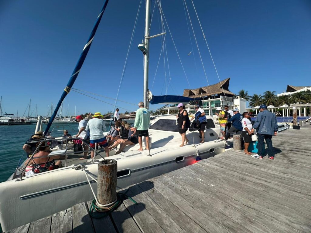 Group of travelers boarding a catamaran for a guided boat trip in Isla Mujeres during their group vacation